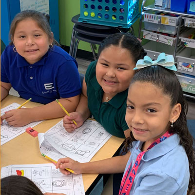 three Empower College Prep scholars sitting at a table doing worksheets