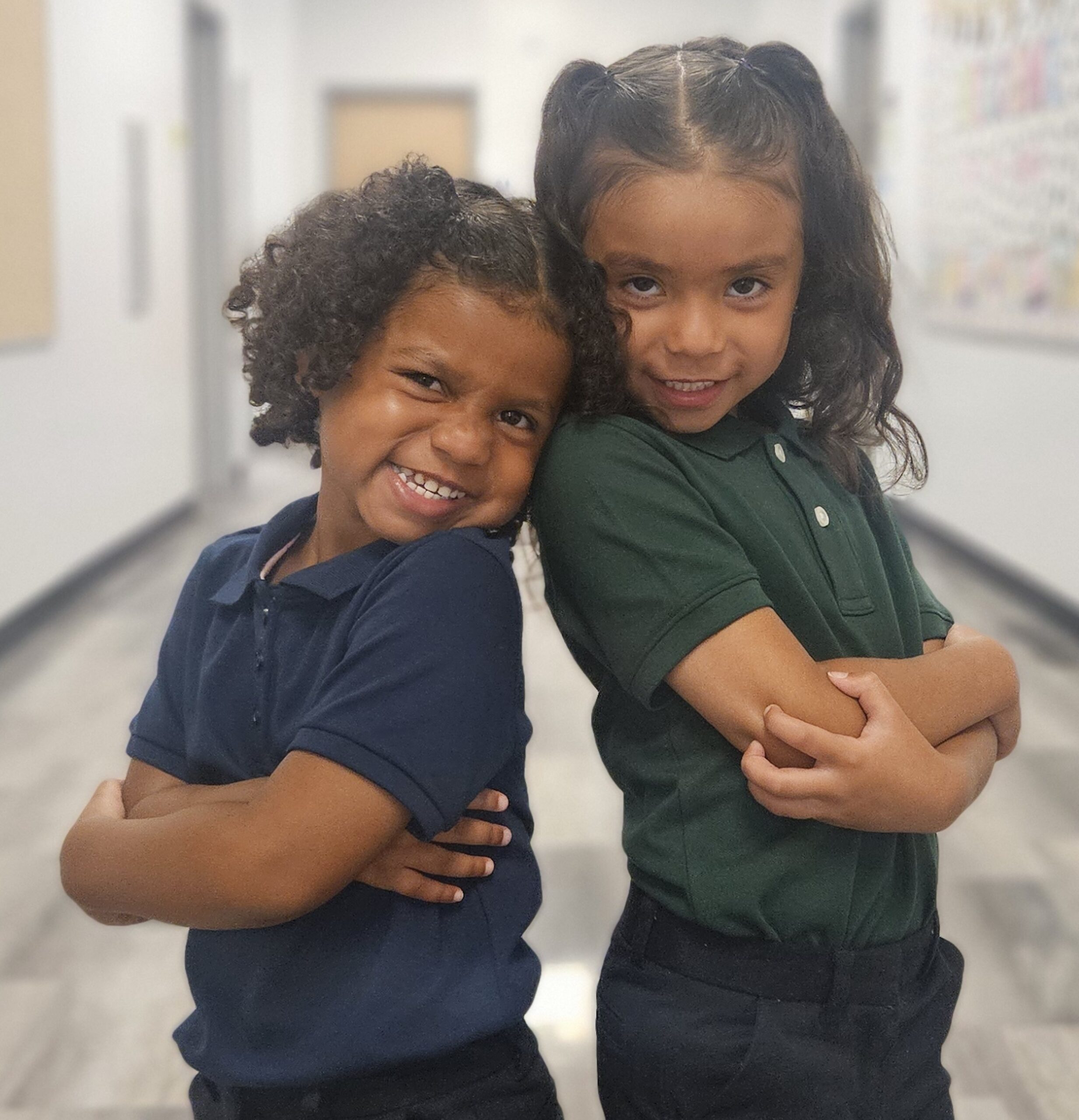 Two Empower College Prep elementary school-aged girls pose for the camera in the school’s hallway.