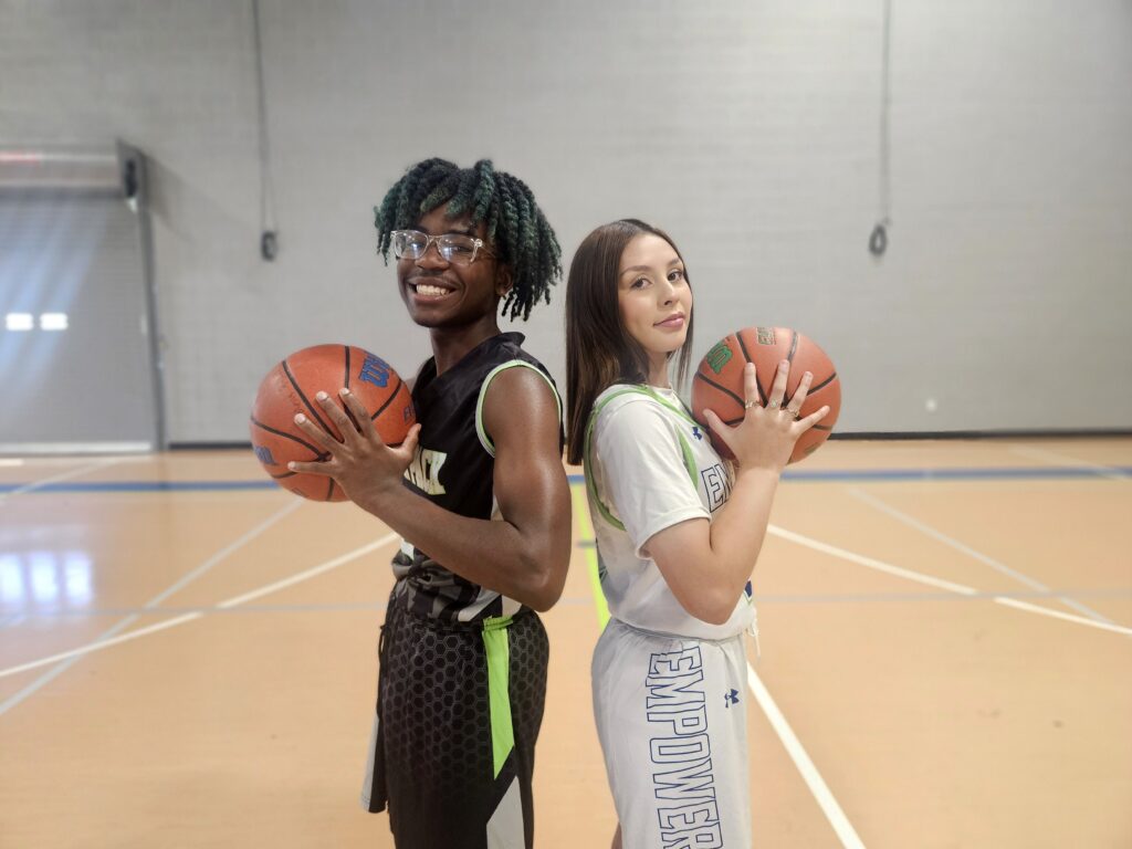 Empower College Prep students dressed in basketball uniforms stand back-to-back and pose for the camera.