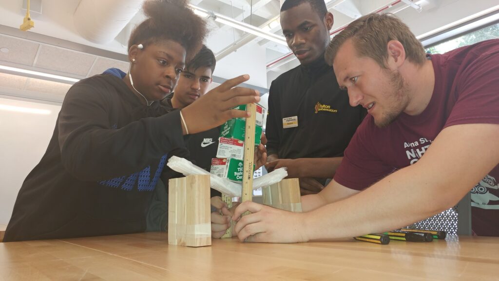 Three Empower College Prep high school students work on a project with their teacher.