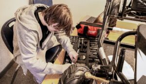 Empower College Prep high school student places tools in a case after completing a hands-on project.