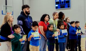 Empower College Prep elementary-school students stand with their teachers after receiving certificates during Advisory.