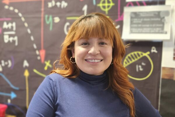 Empower College Prep elementary school math teacher Jessy Aceituno stands in front of a board displaying math formulas.