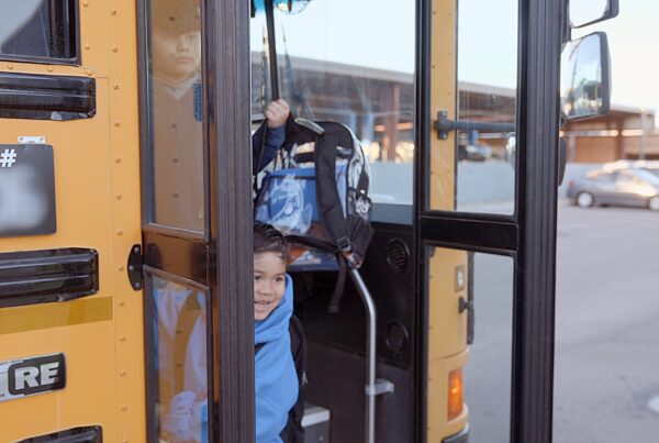 A young Empower College Prep student steps off the school bus arriving at school.