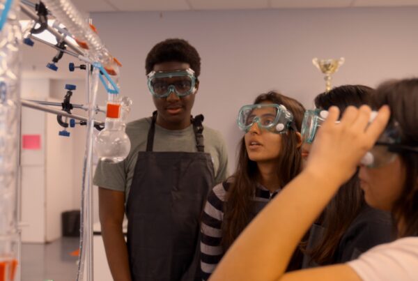3 female and one male Empower College Prep high school students work together on a science experiment.