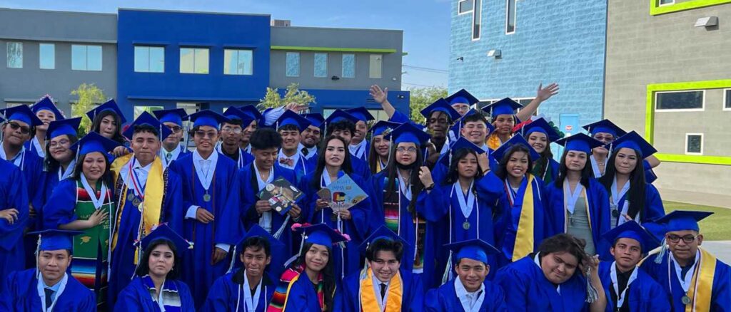 An Empower College Prep class of seniors celebrate their graduation on an outdoor field on campus.