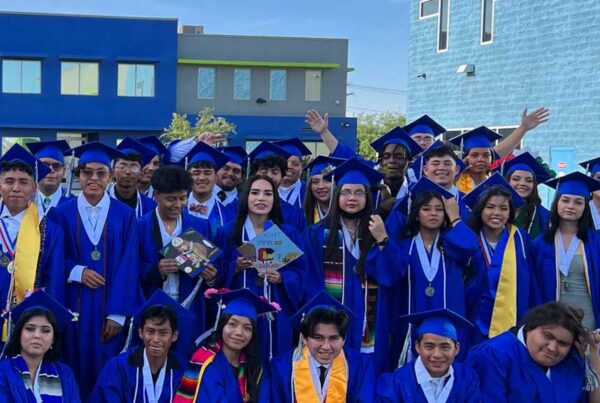 An Empower College Prep class of seniors celebrate their graduation on an outdoor field on campus.