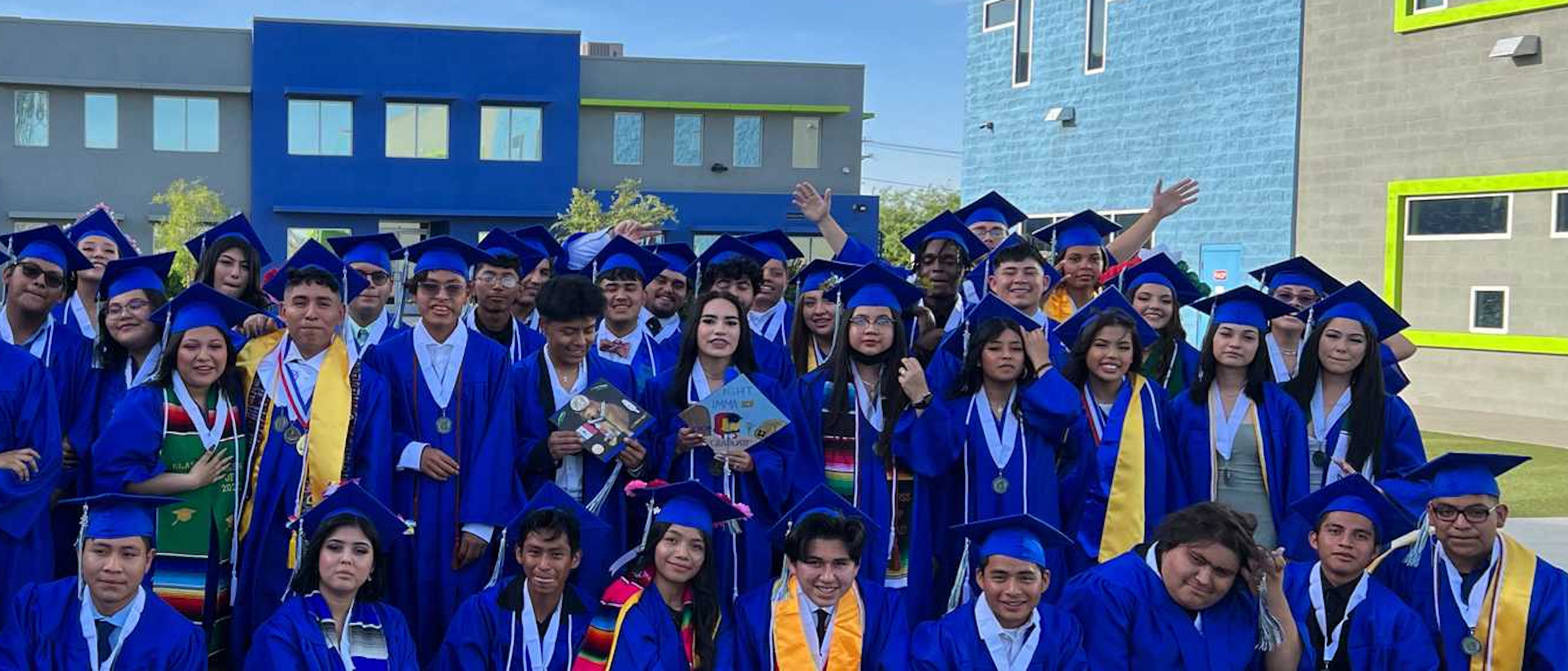 An Empower College Prep class of seniors celebrate their graduation on an outdoor field on campus.