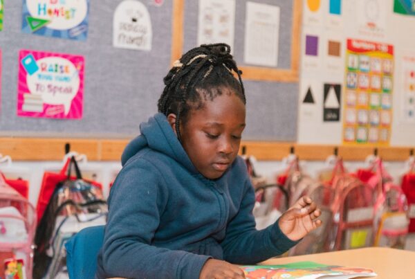 A female Empower College Prep elementary-aged student sits at her desk reading a book