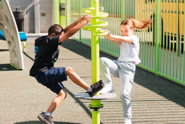 Two Empower College Prep elementary-aged students – a boy and a girl – play together on the school playground.