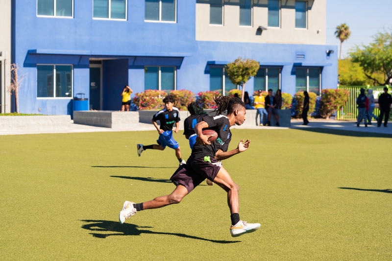 Members of Empower College Prep’s high school football team run down the field during a practice.